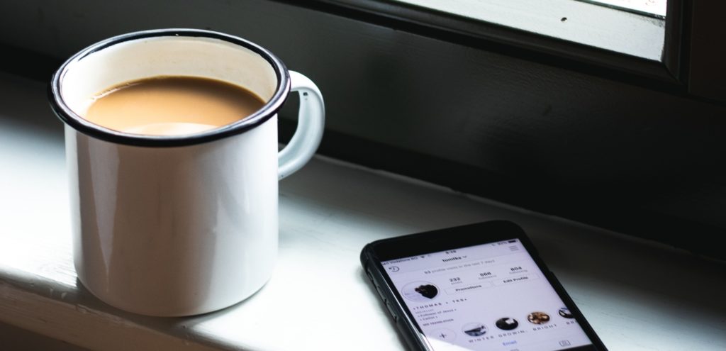 A tea and a phone on a windowsill